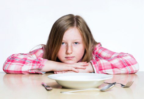 Foto: Ein Mädchen sitzt traurig vor einem leeren Teller. Fotografin: Diana Jill Bader  -  dianajill-fotografie.de